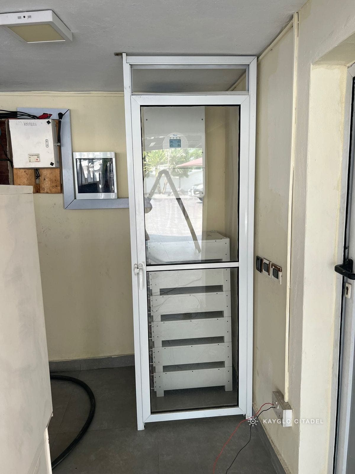 Inverter, changeover panel and stacked battery rack in the glazed plant room.