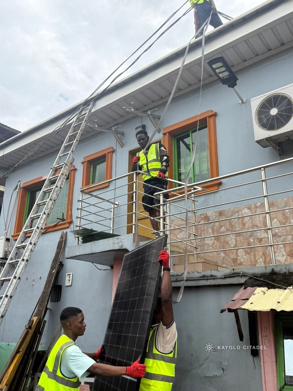 The Kayglo crew hoisting a panel up to the roof from the balcony below.